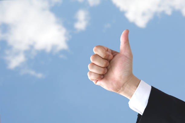 istock Business man's thumbs uo on blue sky background 1420085842