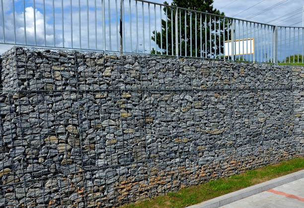 istock construction of a steep staircase by the stone wall car park with high durability even under heavy load galvanized steel floor grate and railings. gabion above him a wire fence. corridor, narrow 1420086928