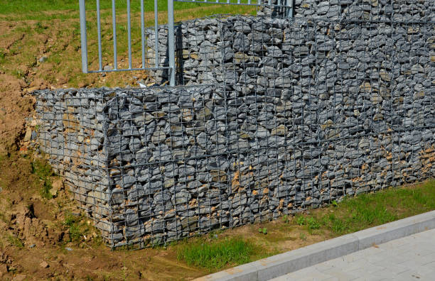 construction of a steep staircase by the stone wall car park with high durability even under heavy load galvanized steel floor grate and railings. gabion above him a wire fence. corridor, narrow, welled construcción de una escalera empinada junto al aparcamiento de pared de piedra con alta durabilidad incluso bajo rejillas y barandillas de suelo de acero galvanizado de carga pesada. gavió sobre él una cerca de alambre. pasillo, estrecho