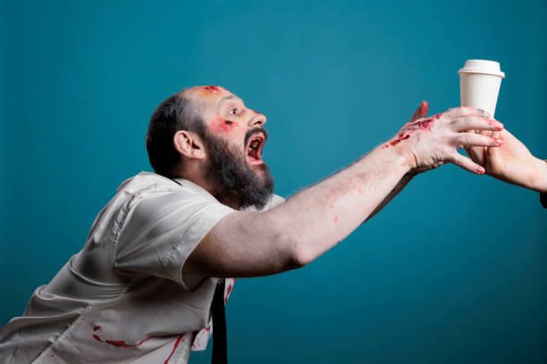 Aggressive zombie wishing to drink coffee cup Aggressive zombie wishing to drink coffee cup in studio, going after beverage and wanting to eat carbon. Spooky undead scary devil chasing hand with drink, acting dangerous and creepy. gross coffee stock pictures, royalty-free photos & images