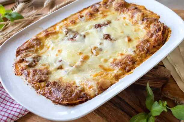 Traditional fresh cooked Lasagna Bolognese. Served closed with a delicious mozzarella cheese topping on wooden background.