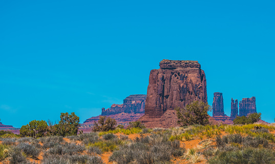 Towering sand stone buttes seen at Monument Valley during a crisp and fresh summer day with blue sky and light clouds. Located on the Arizona and Utah, USA.