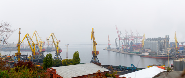 Odesa, Ukraine - OCT 22 2019: Autumn fog in the sea cargo port. Gantry cranes, level luffing cranes in the container terminal and terminal for grains of wheat, soy and other grains and oilseeds