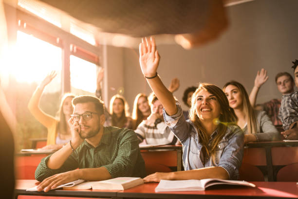 istock Happy students raising their hands on a class at lecture hall. 1420093328