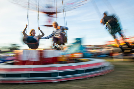 Happy senior couple having fun while riding on a chain swing at amusement park in blurred motion.