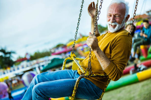 istock Happy mature man having fun on a chain swing ride at amusement park. 1420093958