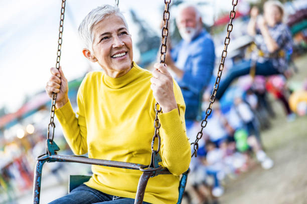 istock Happy senior woman having fun while riding on chain swing at amusement park. 1420093982