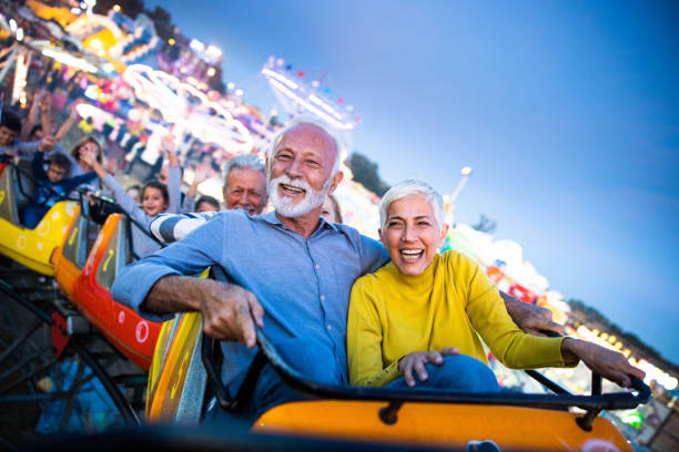 istock Happy senior couple having fun while riding on rollercoaster at amusement park. 1420094247