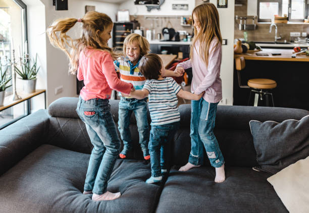 istock Small happy kids having fun while playing on sofa at home. 1420095026