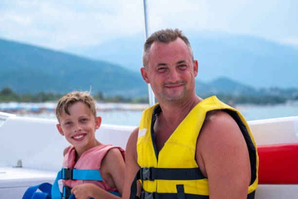 istock Father and son in live jackets sitting on a boat ready for parasailing 1420096267