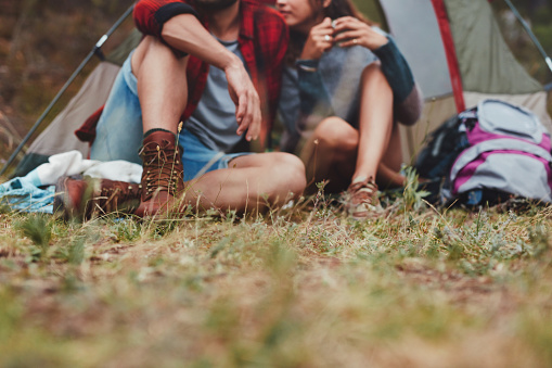 Romantic young couple sitting outside a camping tent. Adventurous young couple enjoying their camping holiday together.