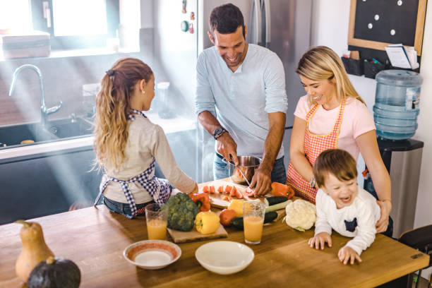 istock Happy parents and their small kids preparing lunch in the kitchen. 1420096444