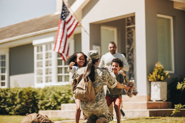 Servicewoman embracing her children on her homecoming Servicewoman embracing her children after arriving home from the army. American soldier receiving a warm welcome from her husband and kids. Military woman reuniting with her family. military lifestyle stock pictures, royalty-free photos & images