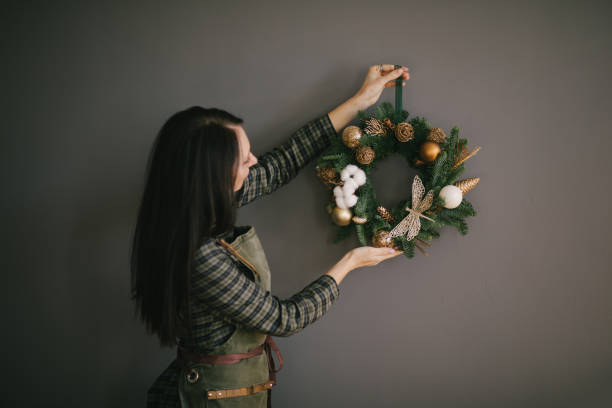 istock Millennial woman making Christmas wreath using natural pine branches and festive decorations in workshop. 1420102342