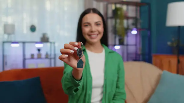 Photo of Woman real estate agent showing the keys of new home house apartment, buying or renting property