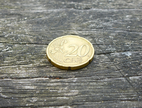 20 cent euro coin laying on a wooden bench.