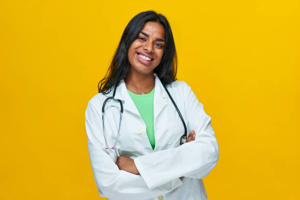 istock Cheerful Indian woman isolated with yellow background, looking at camera while smiling and crossing arms. Concept of an ethnic doctor happy. 1420104233