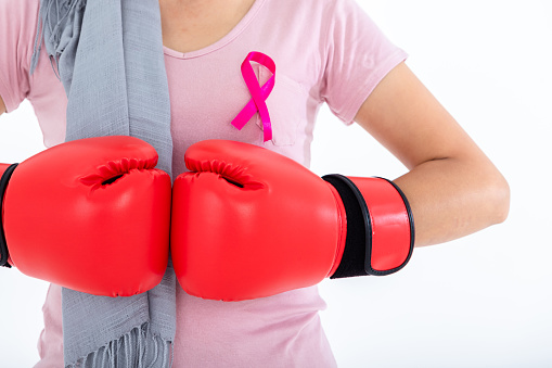 Close up of a asian woman disease mammary cancer patient fighting showing boxing gloves breast cancer awareness month isolated on white blank copy space studio background,healthcare,medicine concept