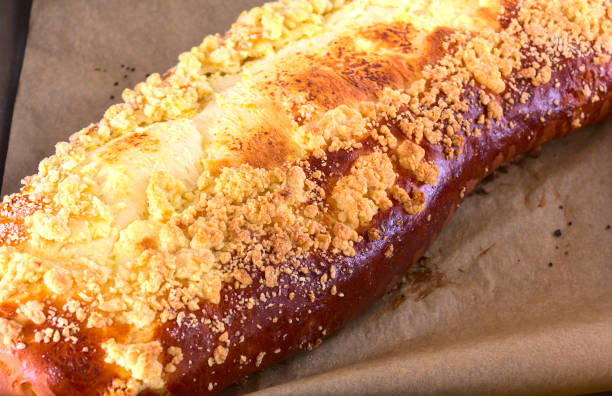 feche acima de um grande strudel de coalhada marrom (fermento-bolo) com crumble. bolo recém-removido do forno em uma assadeira forrada com papel. profundidade rasa de campo. - cheese making - fotografias e filmes do acervo