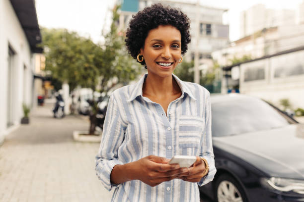 istock Cheerful young woman using a smartphone outdoors 1420106463