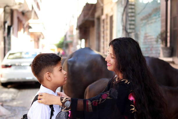 Loving happy mother getting her son for school outdoors, Panipat, Haryana, India.