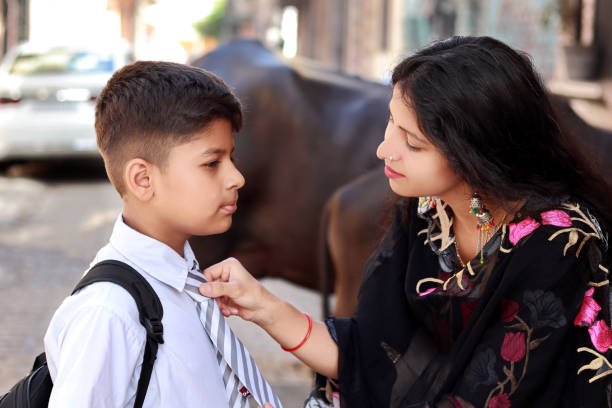 istock Young woman getting her son ready in school uniform 1420107973