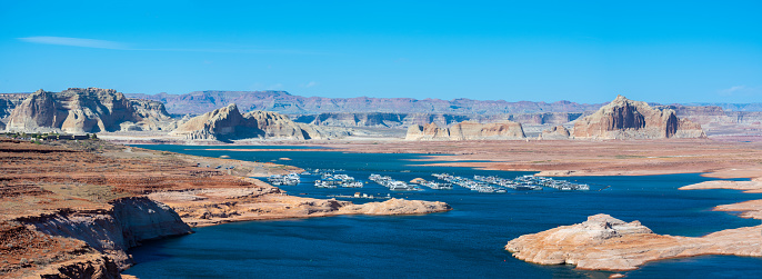 The smooth emerald water of the lake contrasts with the bright red terracotta sandstone shores. Lake Powell. USA. The coast is cut by narrow canyons.