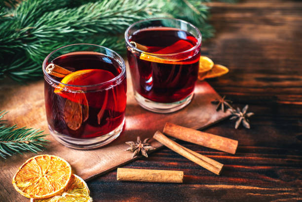 istock close-up on a hot alcoholic drink mulled wine in two transparent glasses with a cinnamon stick, orange and star anise on a dark wooden table against the background of Christmas tree branches 1420109150