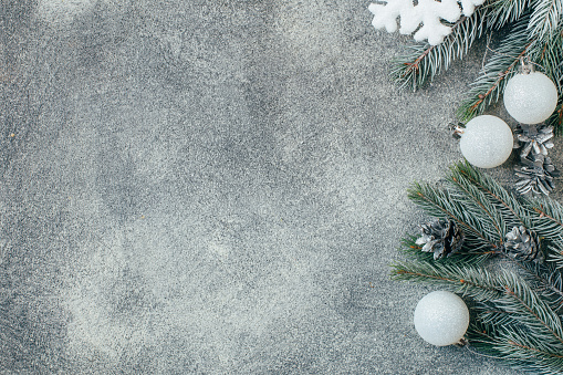 top view of a gray concrete background Christmas decorated with branches of a Christmas tree with Christmas decorations pine cones with free space for text