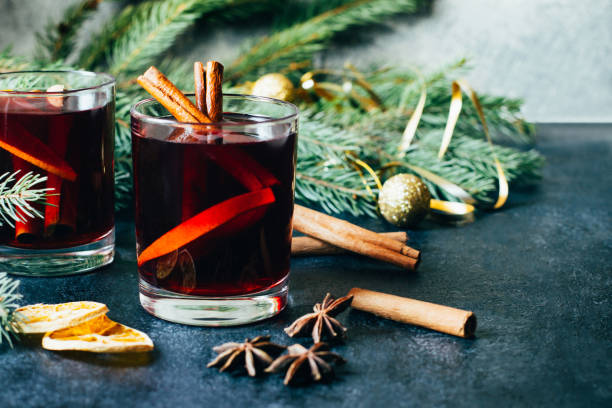istock close-up on a hot alcoholic drink mulled wine in two transparent glasses with a cinnamon stick, orange and star anise on a dark  table against the background of Christmas tree branches 1420109247