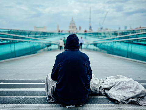 Color image depicting the rear view of a homeless man begging for money in central London, UK.