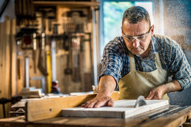 Mature man cutting wood in workshop stock photo