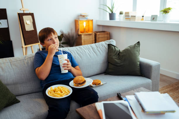 ファーストフードを食べる太りすぎの10代の男の子 - overweight child eating hamburger ストックフォトと画像
