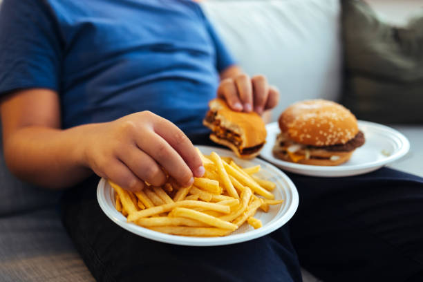 męskie ręce jedzące frytki - overweight child eating hamburger zdjęcia i obrazy z banku zdjęć