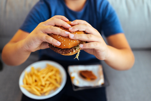 Hungry young man holding tasty hamburger