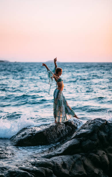 istock Woman Dancing on the Cliffs on the Beach at Sunset 1420116707