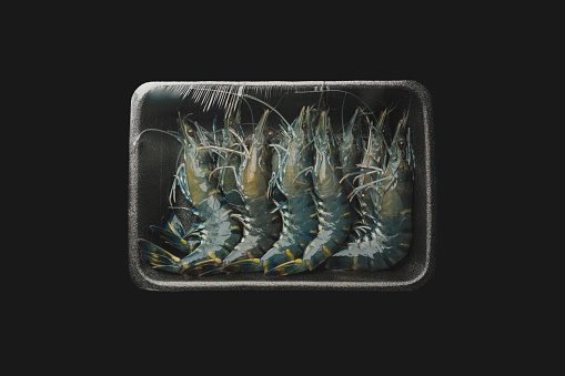 Fresh food - A newly sealed packaging containing tiger shrimps on black background