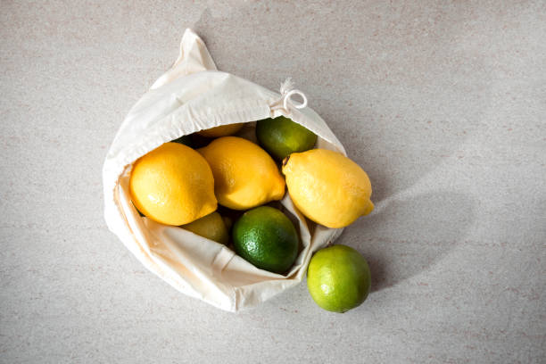 istock Fresh lemons and limes in a fabric bag on a light stone background 1420120363