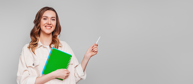 Portrait of a young caucasian woman with a pen and notobook, notepad isolated over white background, student, freelancer. web banner. copy space