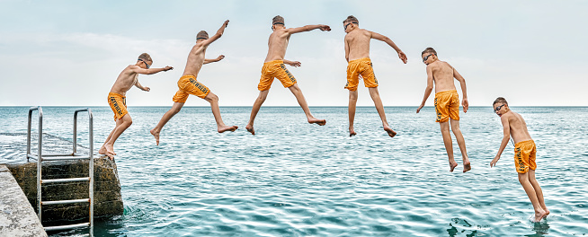 istock Sequence of jump. Moments of schoolboy jumping from pier into sea doing tricks 1420127128