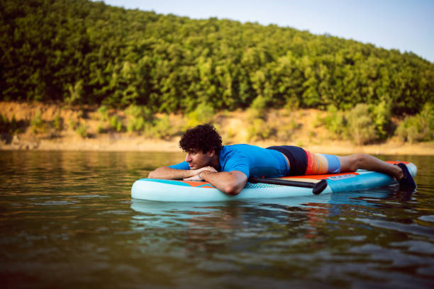 istock Caucasian man lying on a standup paddleboard, while enjoying the view 1420127182