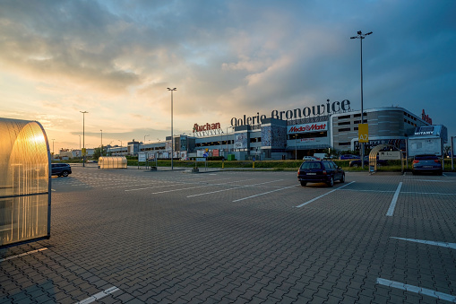 Krakow, Poland - June 25, 2022: An almost empty open parking area or space against supermarket mall or galeria during sunset