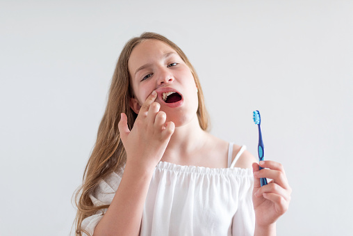 A teenage girl is brushing her teeth