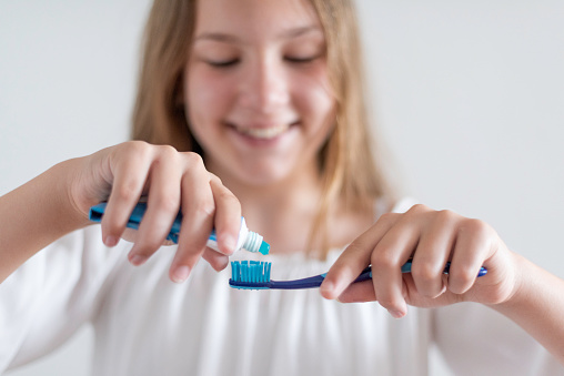 A teenage girl is brushing her teeth