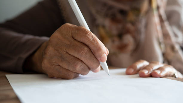 istock old woman writing with pen 1420138161