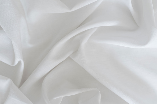 White drapery linen fabric background. Texture of the light surface of the fabric. High quality photo