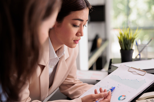 Employees analyzing financial report statistics on clipboard, woman pointing at charts on documents. Start up workers planning business strategy, discussing company research results