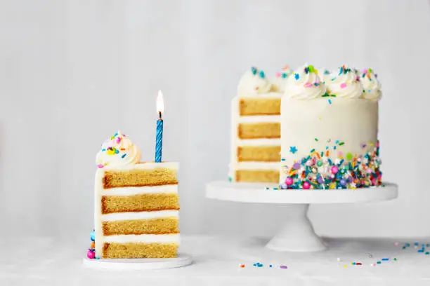 Sliced birthday cake with blue birthday candle and colorful sprinkles