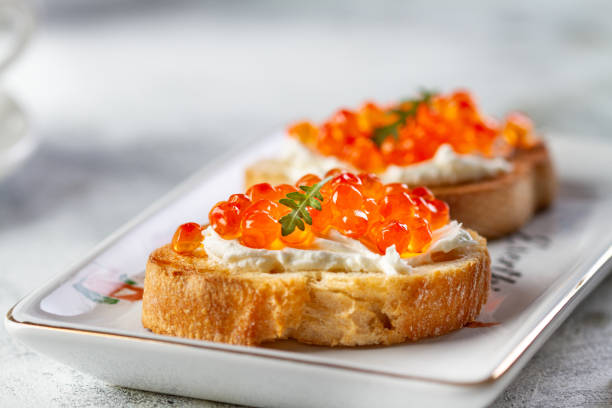 Bruschetta with cheese and red caviar Bruschetta with cheese and red caviar on a plate, close-up caviar stock pictures, royalty-free photos & images