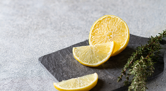 Lemon with a slice and thyme on a slate board, copy space